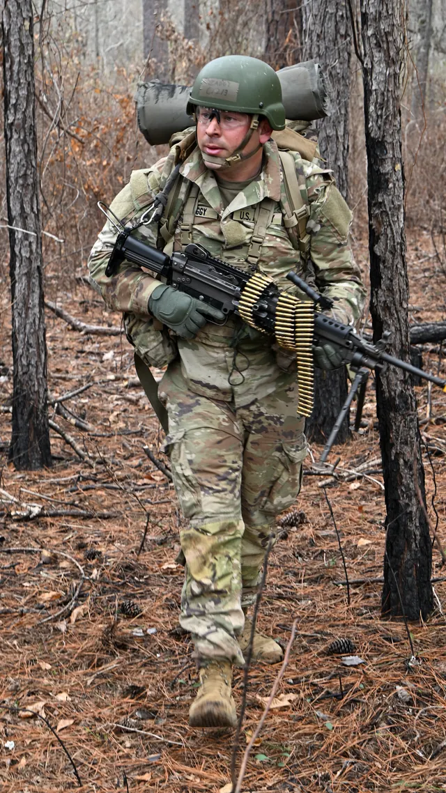 Nick Zaggy carrying field equipment through a pine forest.
