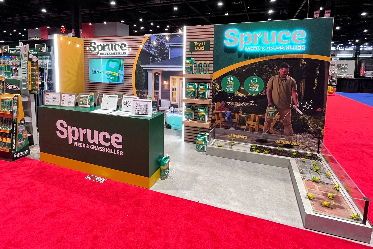Spruce trade-show booth with a neon sign, a product counter and a demonstration garden.